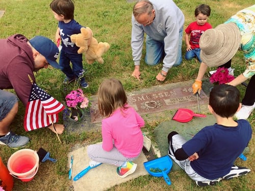 four children and 3 adults clean and decorate grave of family member who served in the military