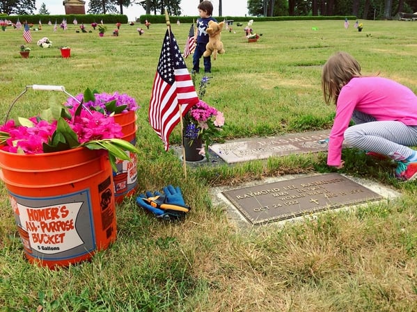 young girl cleans and decorates grave of family member who served during WWII