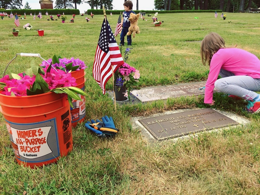 young girl cleans grave of family member who served in the military during WWII 